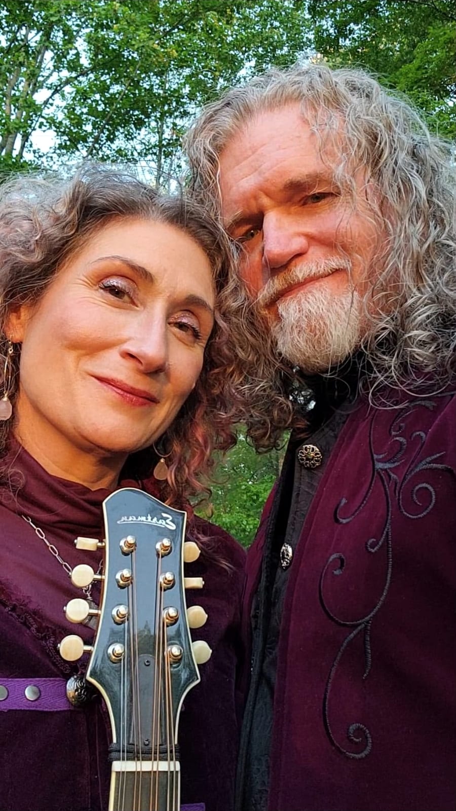 Kristi and Steven in purple velvet outdoors, a mandolin between them